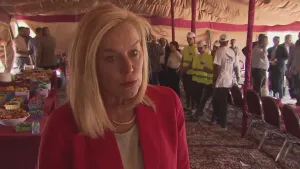 Foto van presentator met op de achtergrond grote tent met meerdere mensen erin.