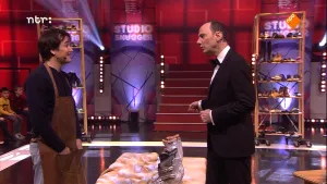 Foto van presentator in de studio van Snugger die staat bij een schoonmaker aan tafel met daarop een aantal schoenen.