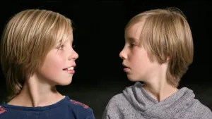 Foto van de hoofden van twee jongetjes, een tweeling, die naar elkaar kijken.