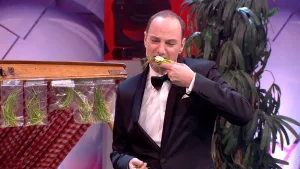Foto van presentator die op de studio een toastje/cracker met gras erop eet.