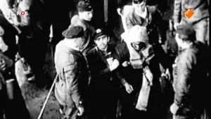 Foto van NOS-Journaal waarop je een oude zwart/wit foto ziet van aantal soldaten bij elkaar ten tijde van de Bevrijding.