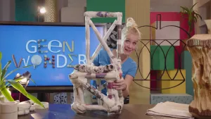 Foto van presentator die een stoel gemaakt van kranten vasthoudt in de studio.