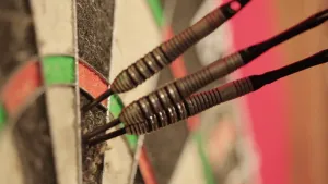 Foto, close-up, van drie dartpijlen die alle drie vlak bij elkaar in een dartbord zitten.