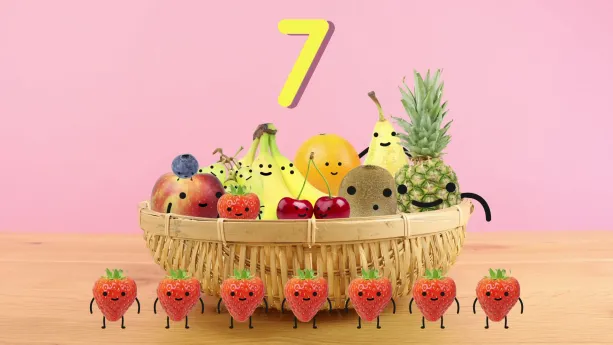 Tekening van fruitmand met stukken fruit met gezichtjes erin, ervoor staan zeven aardbeien met gezichtjes, erboven het cijfer zeven.