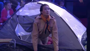 Foto van vrouw die 's avonds uit een kleine kampeer tent kruipt.
