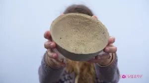 Foto van iemand die een klein rond schaaltje vasthoudt gemaakt van gebruikt wc-papier.