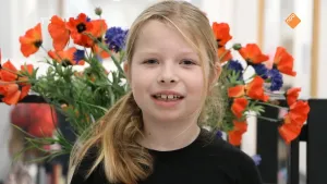 Foto, portret, van een meisje met op de achtergrond grote bos bloemen.