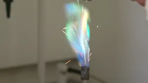 Foto van een grote felle kleurrijke vlam uit een brander, naast wit, oranjegeel en blauw ook groen.