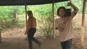 Foto van twee vrouwen onder soort tentafdak in de natuur, de ene vrouw houdt een soort metalen emmertje vast.