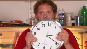 Foto van presentator die een grote ronde klok vasthoudt.