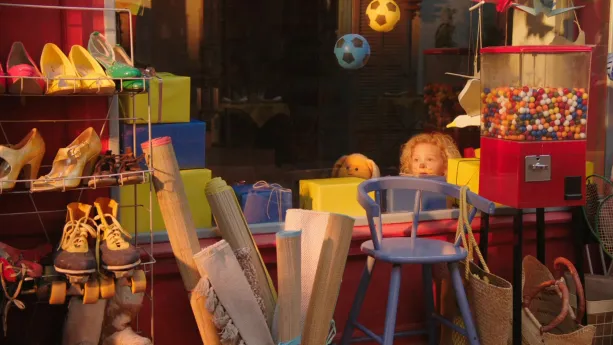 Foto van kinderkamer waar je allerlei speelgoed ziet en je ziet het hoofd van Dropje (stoffen pop) en het hoofd van een meisje.