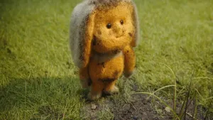 Foto van dierachtig stoffen figuurtje (pop) die staat op het gras, Dropje.