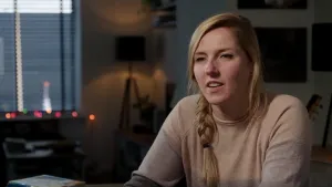 Foto van een vrouw/meisje dat iets vertelt, in een donkere huiskamer.