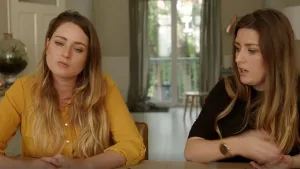 Foto van twee vrouwen aan tafel/bureau in een huiskamer.