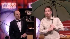 Foto van Studio Snugger met twee mannen op het podium, één van hen houdt een paraplu vast, verder staat er een kast.