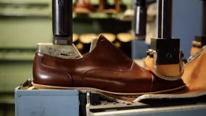 Foto van een schoen in fabriek die wordt bewerkt door een machine.