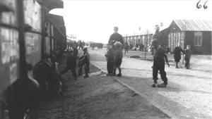 Oude zwart/wit foto van Kamp Westerbork, je ziet aantal gevangenen, ook kinderen, en barakken.
