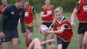 Foto van jonge jongens in sportkleding met een rugbybal die rugby aan het spelen zijn buiten op het veld.