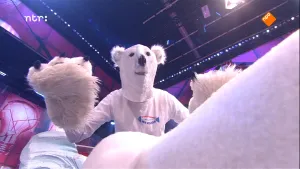 Foto van iemand gekleed als een ijsbeer met grote voorpoten die staat in een hoge donkere zaal (studio).