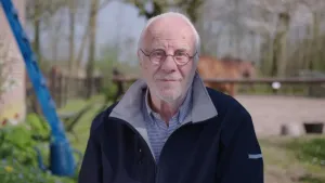 Foto, portret, van een oudere man met bril op buiten in tuin/bos.