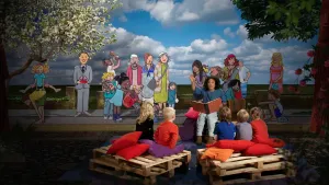 Foto van iemand die voorleest aan kinderen met op de achtergrond een decor uit een bijbelverhaal.