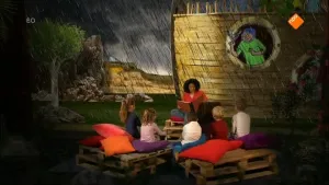 Foto van iemand die voorleest aan kinderen met op de achtergrond een decor uit een bijbelverhaal.