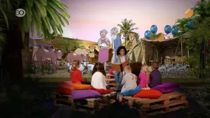 Foto van iemand die voorleest aan kinderen met op de achtergrond een decor uit een bijbelverhaal.