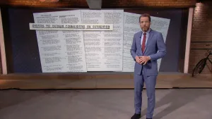 Foto van het NOS-Journaal met nieuwslezer die staat voor een heel grote foto van witte pagina's met tekst erop.