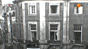 Foto van het NOS-Journaal met erop foto, zwart/wit, van huizen in de stad uit de tijd van de Bevrijding.