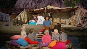 Foto van iemand die voorleest aan kinderen met op de achtergrond een decor uit een bijbelverhaal.