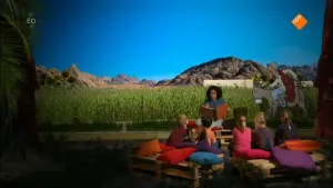 Foto van presentator die aan kinderen voorleest met op de achtergrond foto van berglandschap en gras met erin een getekende ezel waar een man op zit.