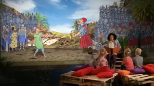 Foto van presentator die kinderen voorleest, zitten op toneel met grote tekening van Goliath en kleine David op de achtergrond.