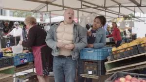 Foto van marktkraampjes met groente, het is er druk, op de voorgrond zie je een man, Willem Wever.