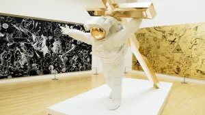 Foto van scène uit het Klokhuis in museum met kunstwerk: een astronaut die een gouden kruis draagt op zijn rug.