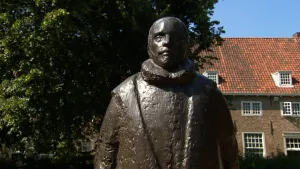 Foto van een beeld van Willem van Oranje met op de achtergrond oude huizen.