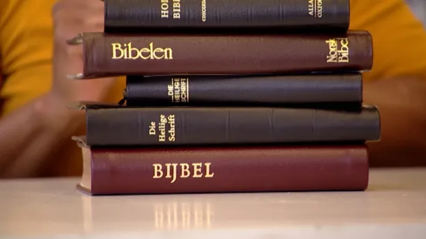 Foto van een stapel Bijbels op een tafel.
