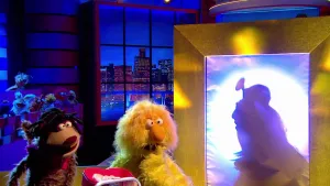 Foto van scène uit de Boterhamshow met Opperdepop en twee figuren in de studio aan tafel, van één alleen het silhouette, arts.