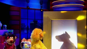 Foto van scène uit de Boterhamshow met Opperdepop aan de desk met twee figuren (poppen), één van hen zie je alleen het silhouette, kok, in de studio.