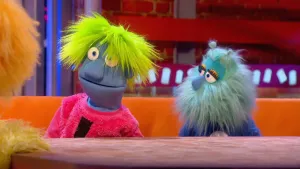 Foto van scène uit de Boterhamshow met Fons Mega en Liz Quiz aan de desk en je ziet nog deel van Opperdepop.