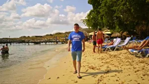 Foto van Ersin die wandelt op een strand met badgasten te Curaçao.