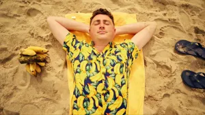 Foto van man die op een gele badhanddoek ligt op het strand, close-up.