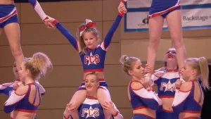 Foto van kinderen, meisjes, die cheerleader zijn en opvoering geven in gymnastiekzaal.