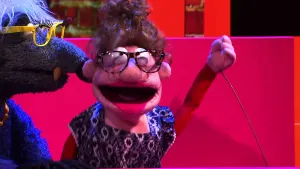 Foto van scène uit de Boterhamshow met twee figuren in de studio die optreden, een lied zingen.