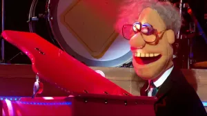 foto van scène uit de Boterhamshow met portret van Drs. Nee (pop) die zit aan een vleugel/piano en zingt, in de studio.