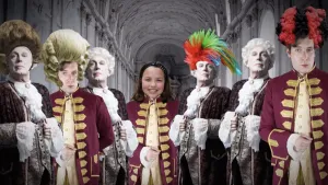 Foto van mensen in 17e-eeuwse kleding met hoge pruiken op, met in het midden een hedendaags kind. 