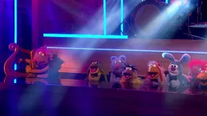 Foto van scène uit de Boterhamshow waarbij aan de desk meerdere figuren (poppen) zitten in de studio.