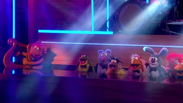 Foto van scène uit de Boterhamshow waarbij aan de desk meerdere figuren (poppen) zitten in de studio.