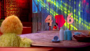 Foto van scène uit de Boterhamshow met Opperdepop en Pi R Kwadraat aan tafel, erbij een vier, een afgedekte vijf, een zes.