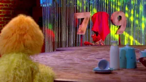 Foto van scène uit de Boterhamshow met Pi R Kwadraat en Opperdepop aan tafel (poppen), je ziet een zeven, een afgedekte acht, een negen.