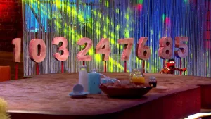 Foto van scène uit de Boterhamshow waarbij je reeks cijfers, nul tot en met negen, waarbij Pi R Kwadraat (pop) zit aan tafel.